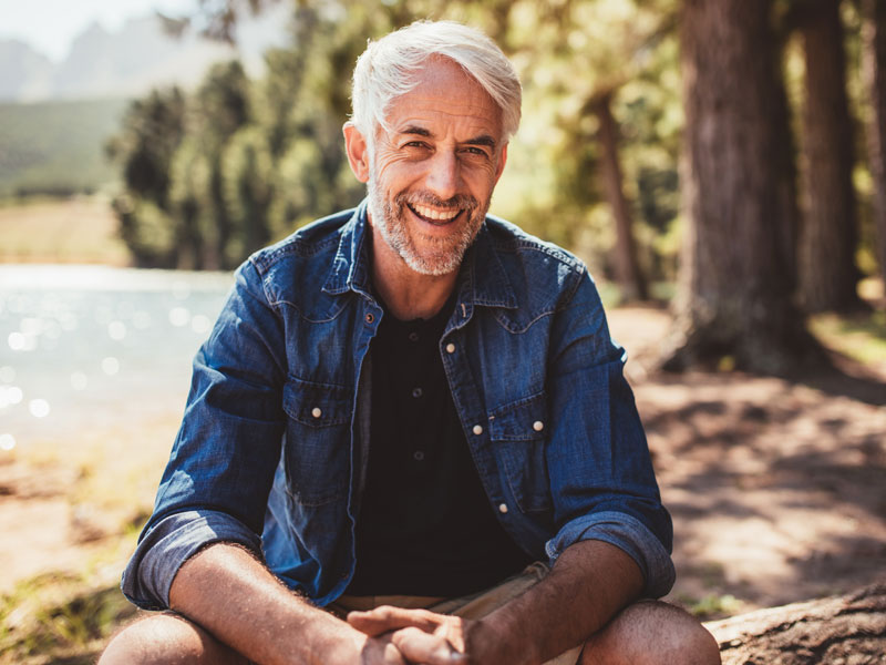 older man outside in park near a lake