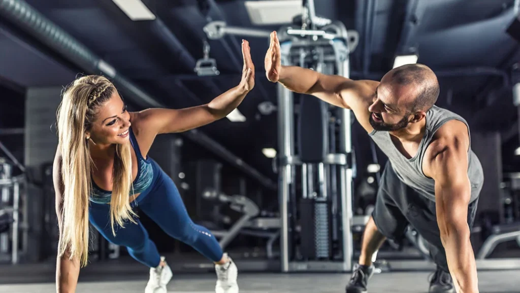 Two workout partners celebrating with a high-five in a gym.